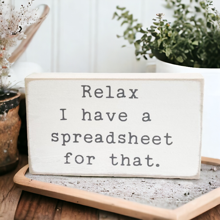 A 3.5" x 6" wood desk sign in crisp white with playful typewriter gray text that reads, 'Relax, I have a spreadsheet for that..