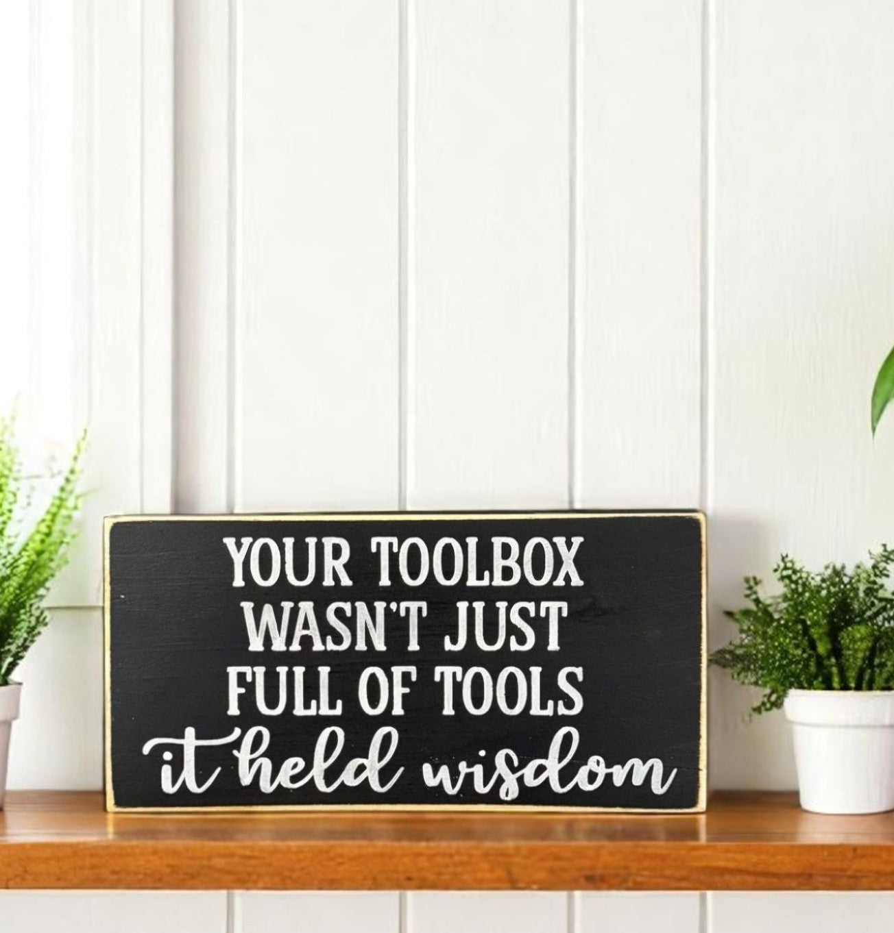 Handpainted black wood sign with white text that reads “Your toolbox wasn’t just full of tools – it held wisdom,” a heartfelt gift idea for Dad.