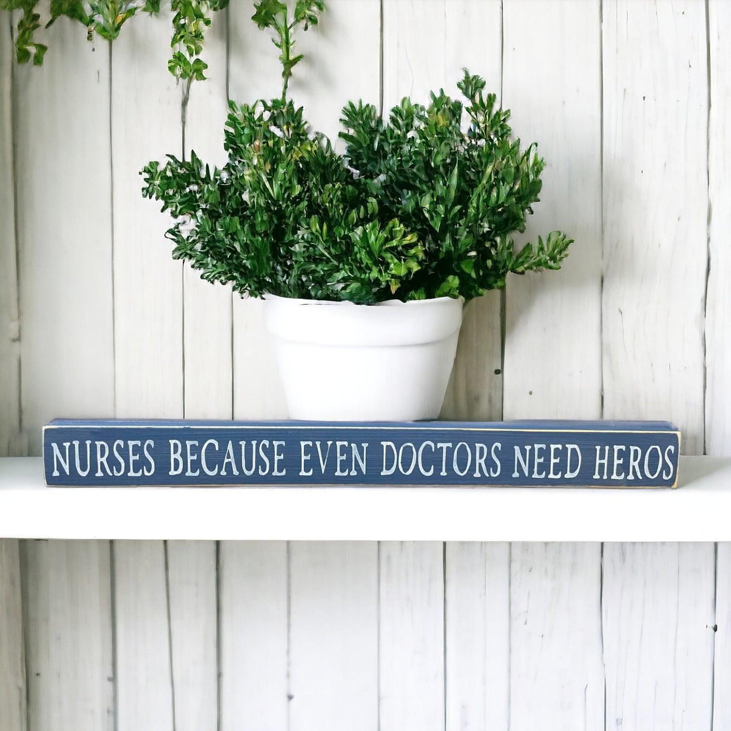 Handpainted bluish-gray wood sign with white text reading 'Nurses Because Even Doctors Need Heroes,' freestanding 16-inch gift decor for nurses.