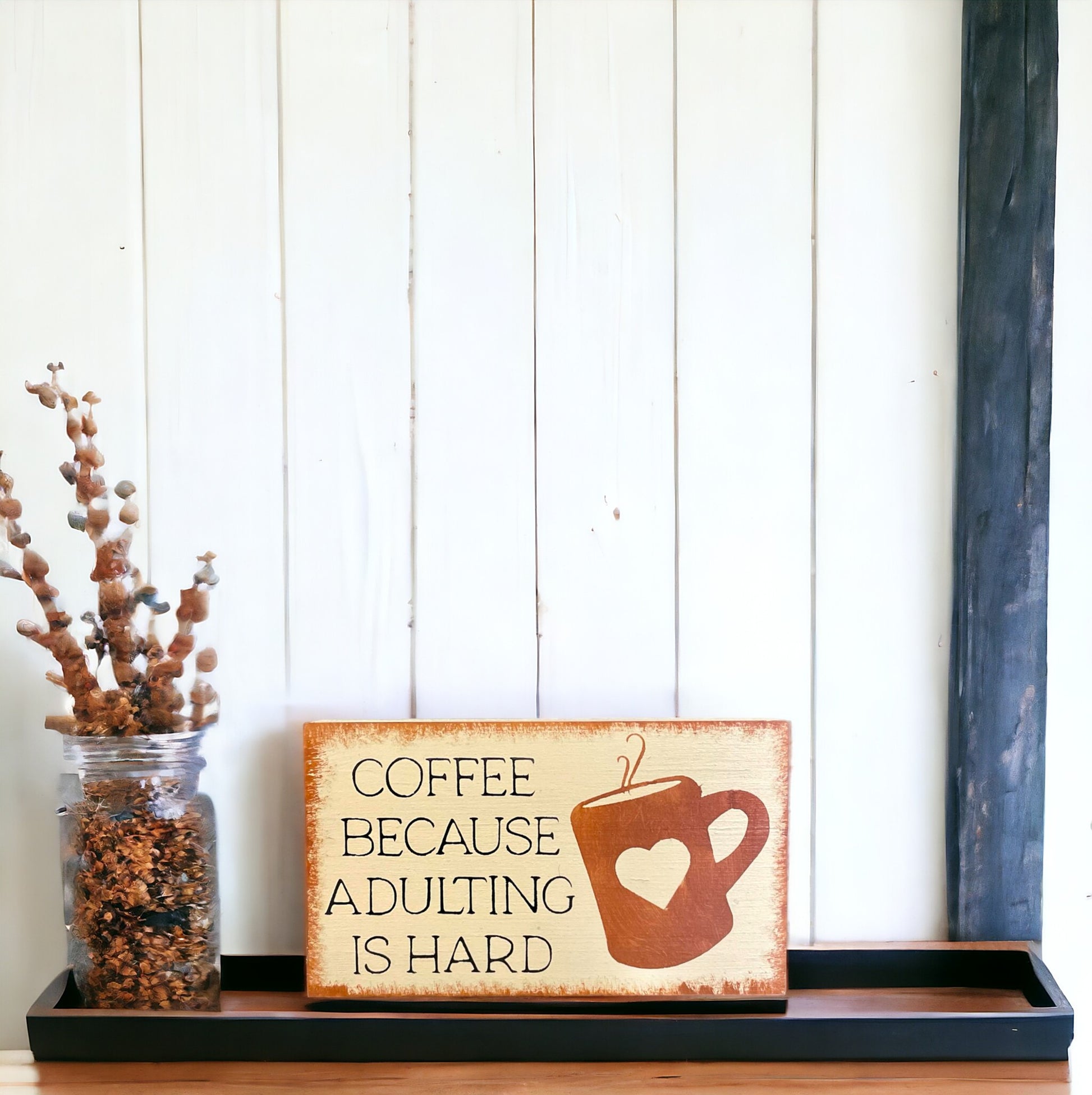 Wooden coffee sign with mug illustration and text: 'Coffee Because Adulting Is Hard'