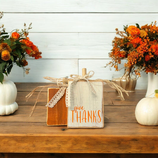 Handcrafted wood pumpkins for Thanksgiving decorations—one orange and one distressed white with "Give Thanks," perfect shelf sitters for fall decor.