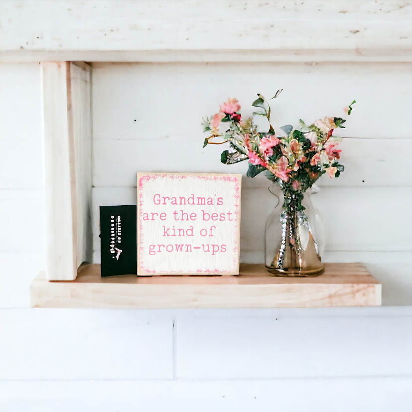 A 4.5" x 4.5" wood sign with a white background, playful pink text, and a vibrant pink border, featuring the message, 'Grandmas are the best kind of grown ups.' This charming grandma sign adds a playful and loving touch to your decor, making it an ideal gift or a delightful addition to your space.