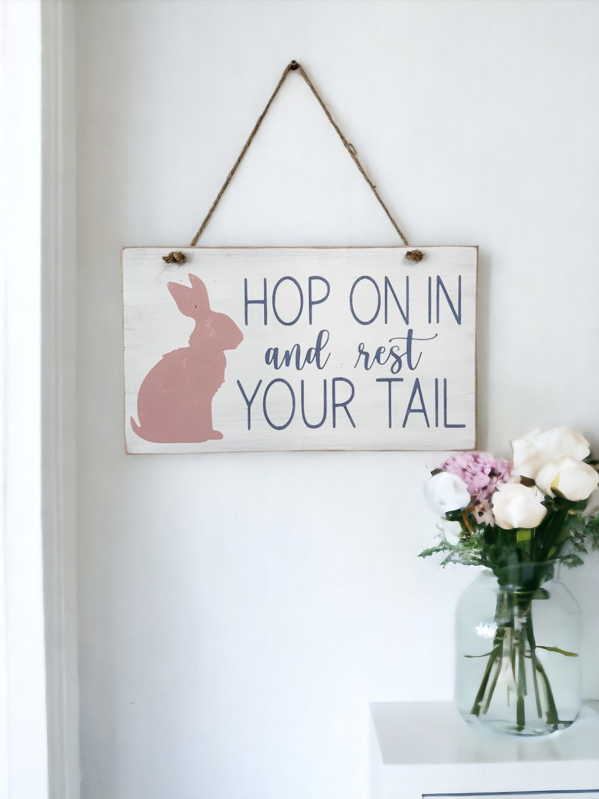 7" x 12" hanging wood sign with 'Hop On In And Rest Your Tail' in lavender text and a pink bunny, ideal for farmhouse Easter decor