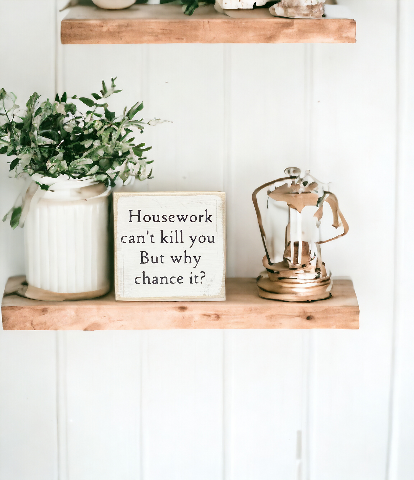 A 4" x 4" wood block sign featuring rustic golden oak stained sides and back, with an antique white front and bold black text that reads, 'Housework Can't Kill You, But why chance it?' This freestanding sign is the perfect addition to your funny home decor collection, making it an ideal choice for tabletops, mantels, and floating shelves