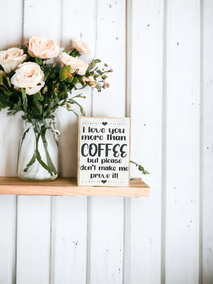 A 3.5" x 5" rustic block sign with a white background and whimsical black text that reads, 'I love you more than coffee but please don't make me prove it.' This coffee sign is a charming addition to any coffee lover's space, adding a cute and funny touch to their coffee bar decor.