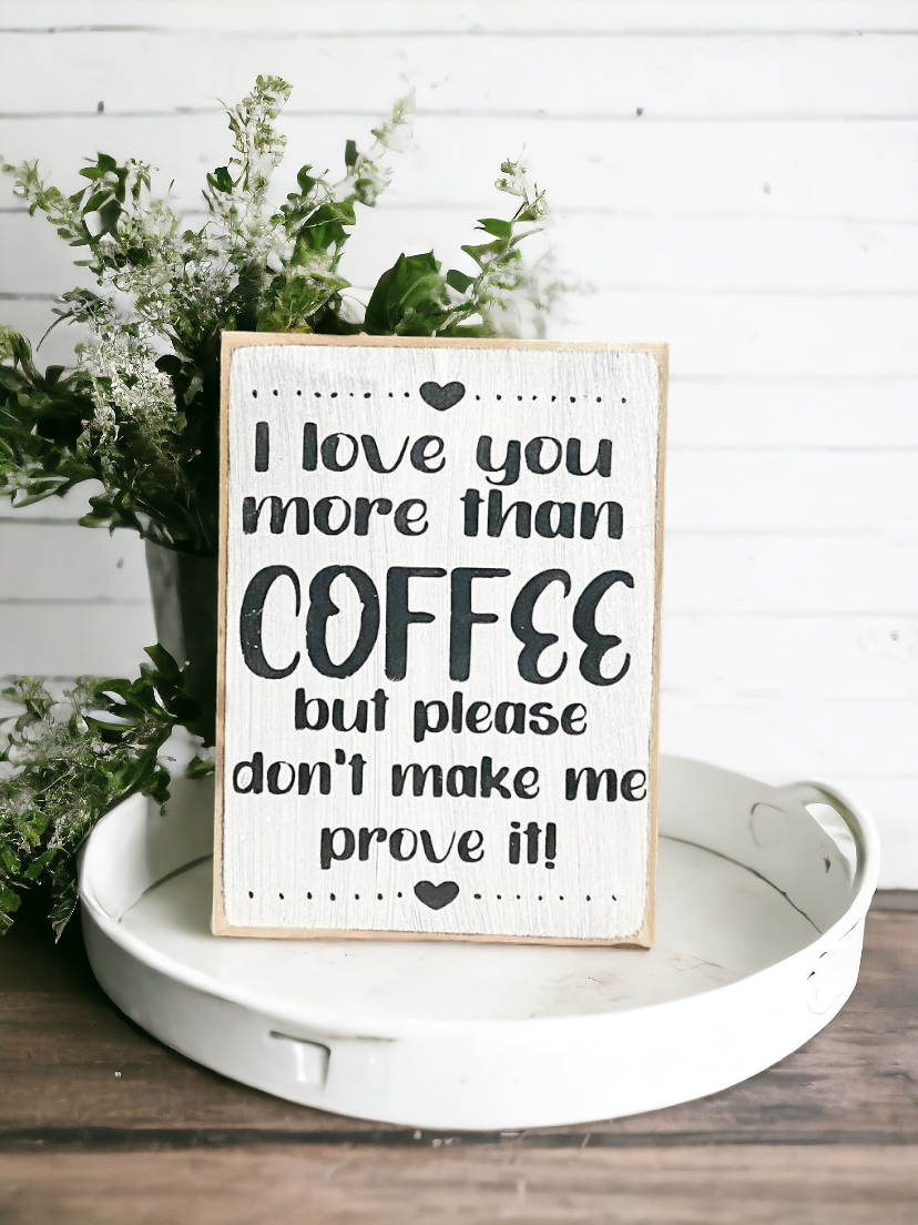 A 3.5" x 5" rustic block sign with a white background and whimsical black text that reads, 'I love you more than coffee but please don't make me prove it.' This coffee sign is a charming addition to any coffee lover's space, adding a cute and funny touch to their coffee bar decor.