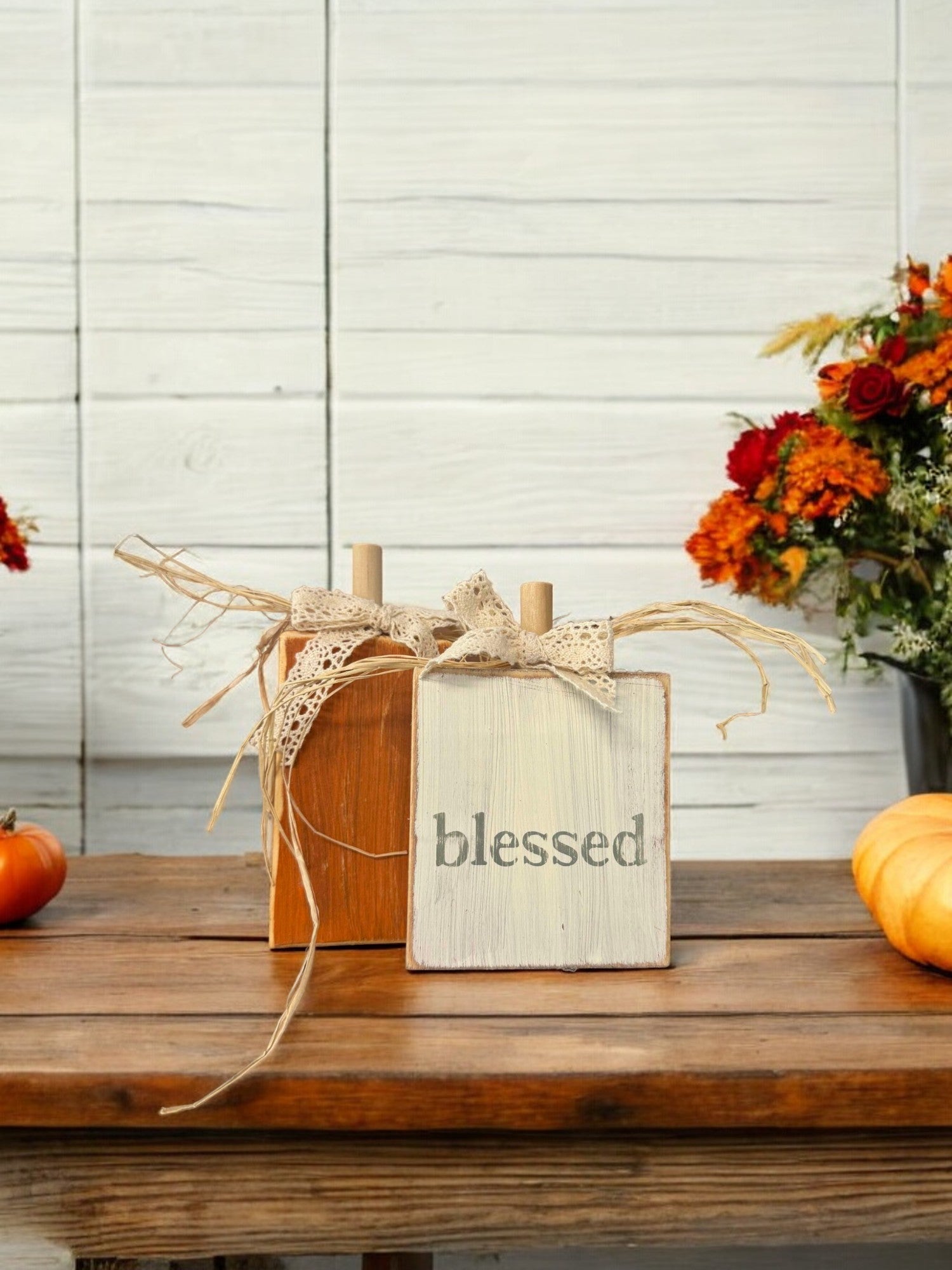 Handcrafted wood pumpkin decorations, one orange and one distressed white with "Blessed" in green, for fall home decor.