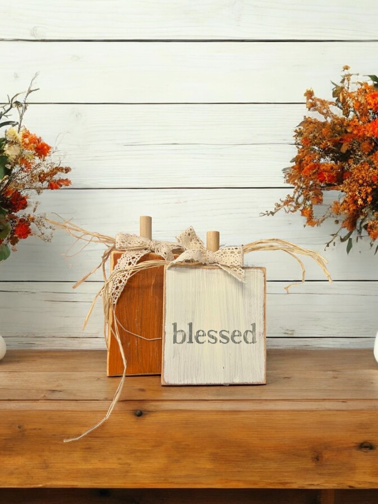 Handcrafted wood pumpkin decorations, one orange and one distressed white with "Blessed" in green, for fall home decor.