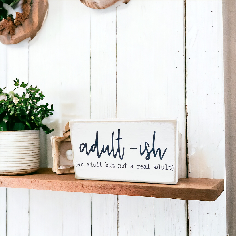 : A 3.5" x 6" wood block sign with a white background and amusing black text that reads, 'Adultish, an adult but not a real adult.' This freestanding sign is the perfect funny office sign, adding a dose of adulting humor to your workspace.