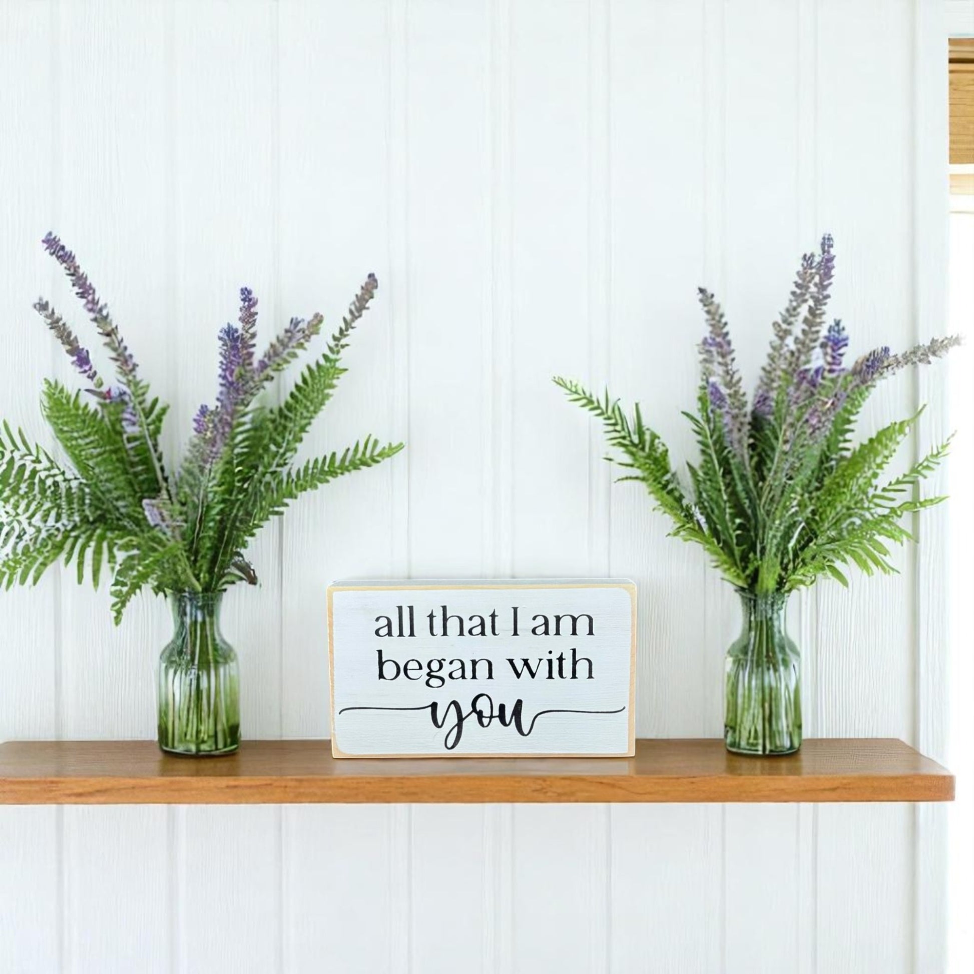 White wooden block sign with black text that reads “All That I Am Began With You” – meaningful gift for Mother’s Day.

