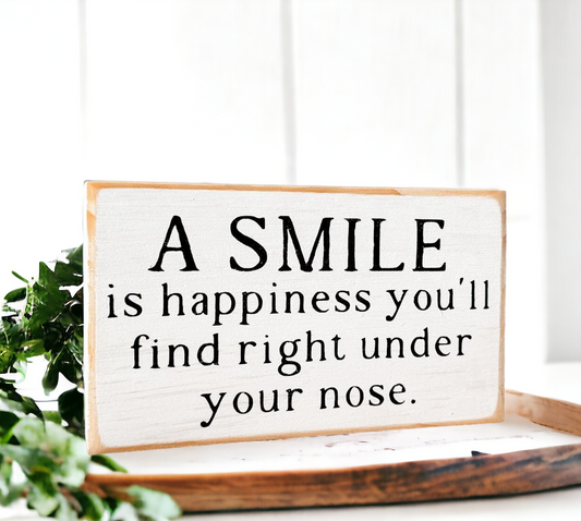 Rustic black and white wood block sign with the happiness quote 'A Smile is Happiness You'll Find Right Under Your Nose.' Ideal decor for home or office. Shop now for this uplifting gift