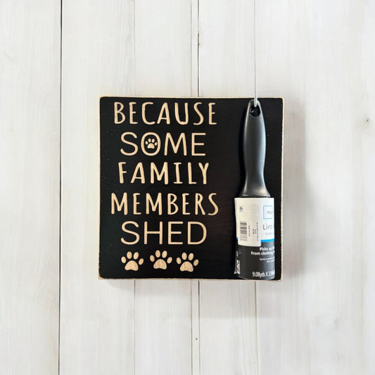 Carved wooden sign reading 'Because Some Family Members Shed,' handpainted black with natural wood lettering. Features a hook for a lint roller, making it a perfect pet lover gift and practical home decor piece