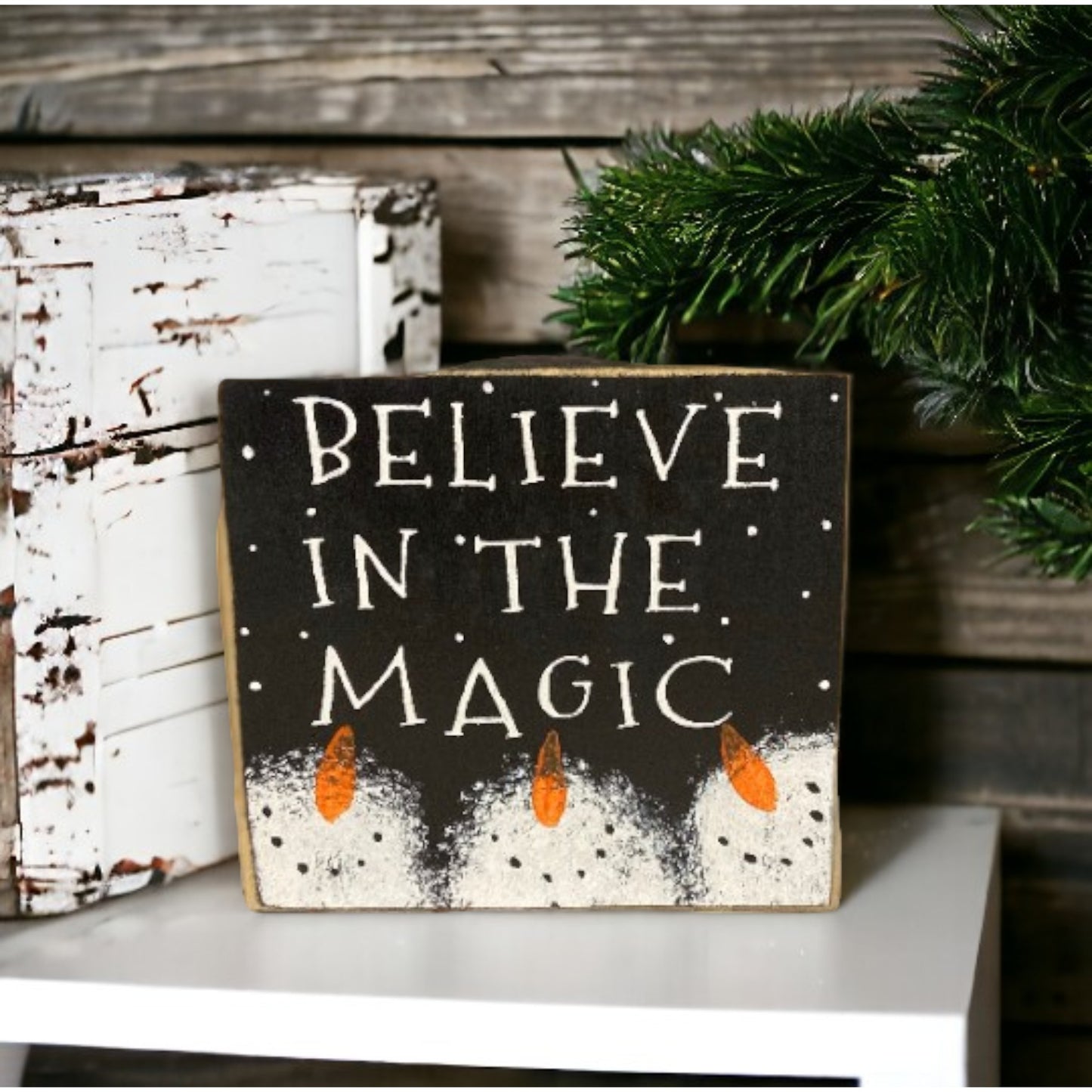 "Believe In The Magic" wood block sign with a black background, white text, and handpainted snowmen, perfect for primitive Christmas decor.