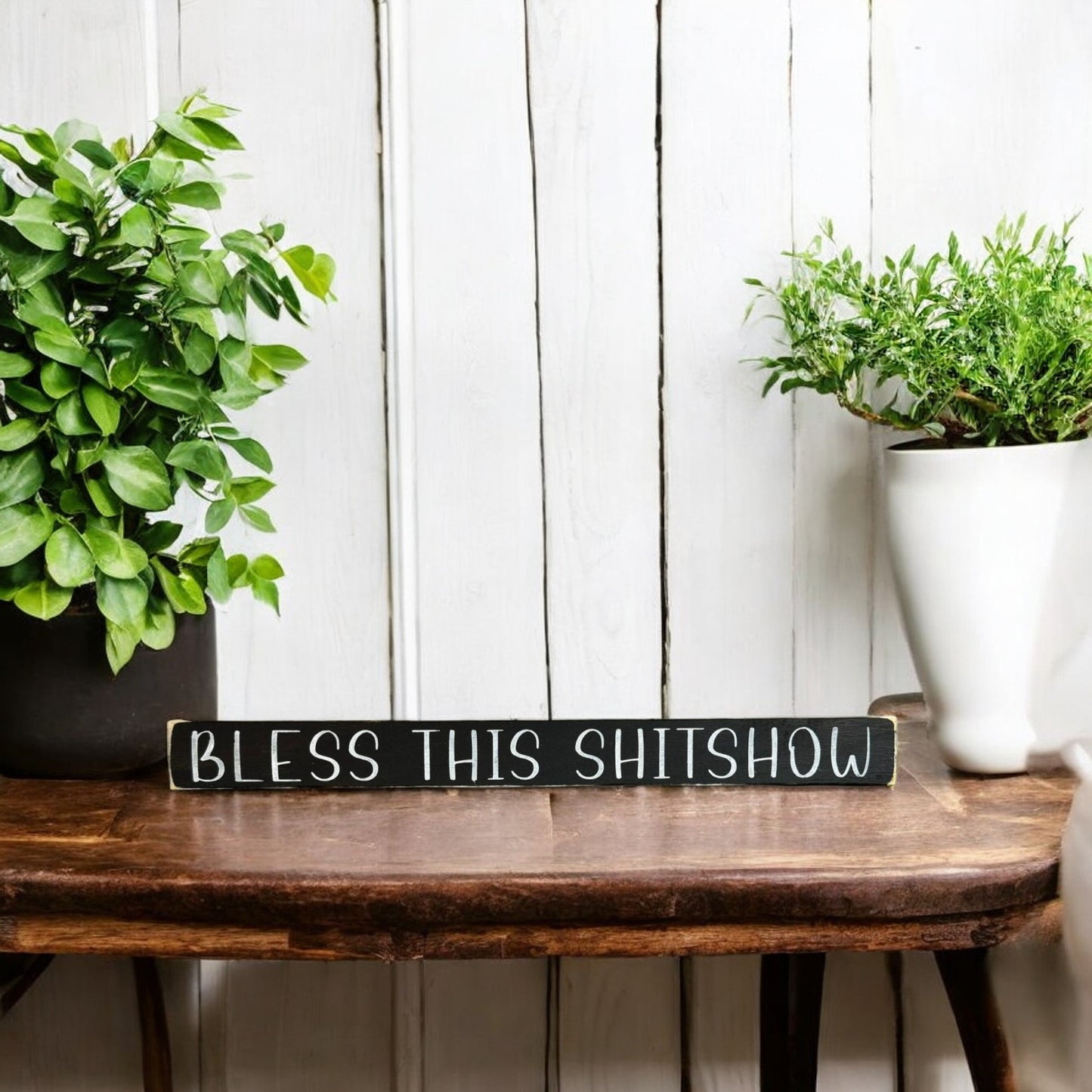 Hand-painted 1.5" x 16" wood shelf sitter sign that reads "Bless This Shitshow" in white text on a black background, perfect for home or office decor and as a funny gift.