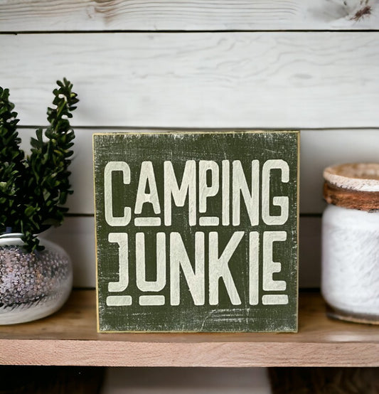 Wood block sign with moss green background and white text that says 'Camping Junkie'