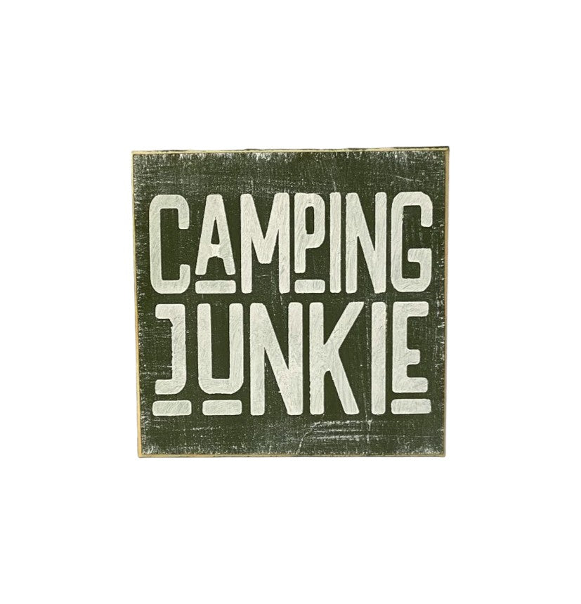 Wood block sign with moss green background and white text that says 'Camping Junkie'