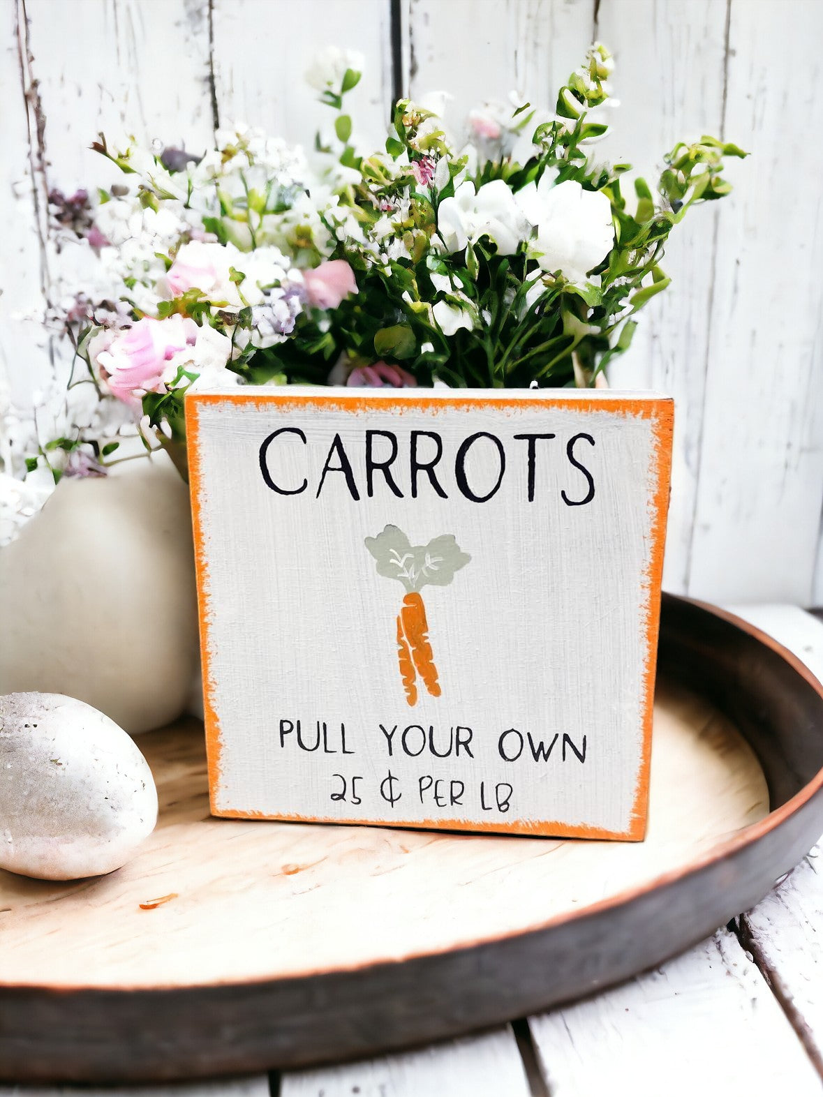"Carrots Pull Your Own 25¢ per lb." wooden Easter sign with hand-painted carrot design on a white background.