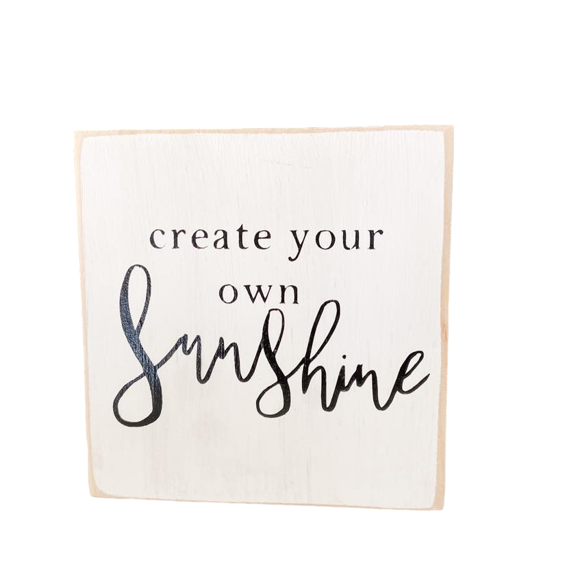 A 4.5" x 4.5" small wood block sign with a white background and bold black text that reads, 'create your own sunshine.' This inspirational wood sign is a perfect desk sign and tabletop decor, serving as a daily reminder to infuse positivity into your workspace.