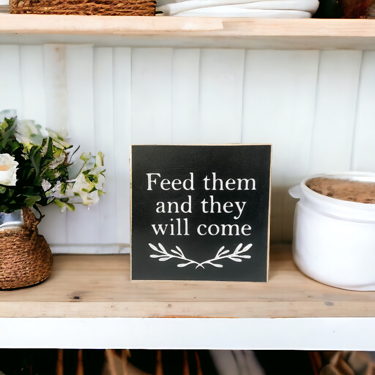 4.5" x 4.5" black wooden sign with white text that reads 'Feed them and they will come.