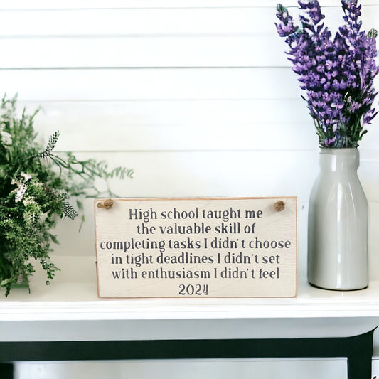 Wood sign with humorous text: 'High school taught me the valuable skill of completing tasks I didn't choose in tight deadlines I didn't set with enthusiasm I didn't feel' - Graduation Gift 2024