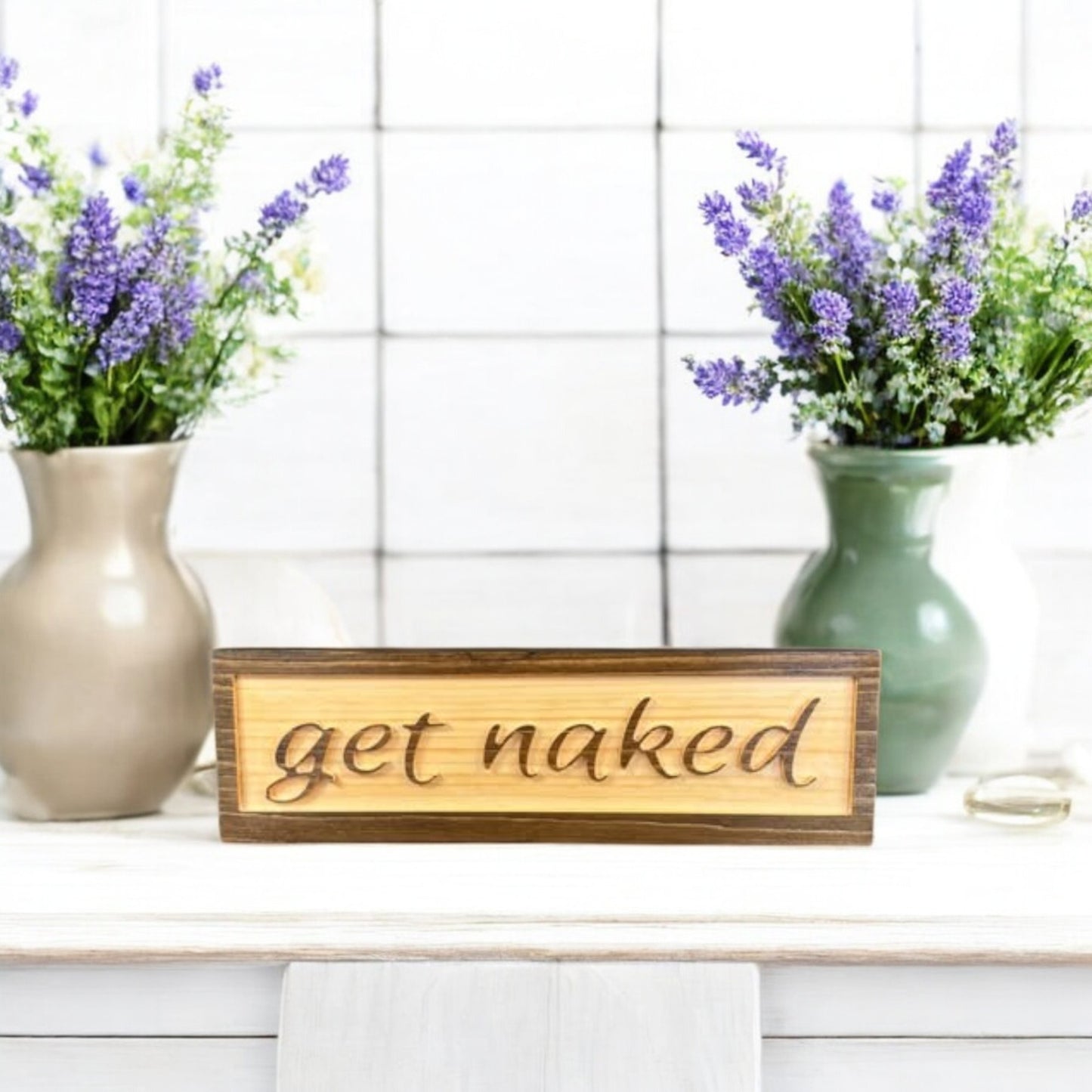 Carved wooden bathroom sign with raised lettering that says "Get Naked," featuring a two-tone stain finish – rustic and funny bathroom decor.