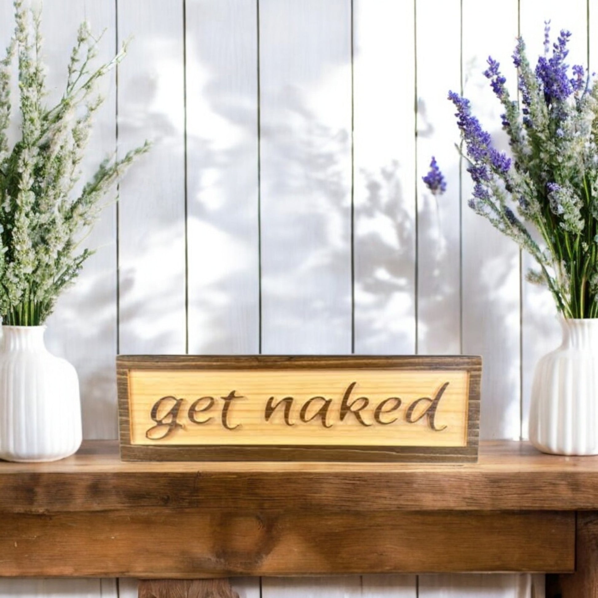 Carved wooden bathroom sign with raised lettering that says "Get Naked," featuring a two-tone stain finish – rustic and funny bathroom decor.