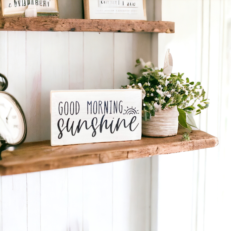 A 3.5" x 6" wood block sign with a white background and sleek black text that reads, 'Good Morning Sunshine.' This wood block sign is the perfect bedside table decor, designed to add a touch of positivity and motivation to your bedroom.