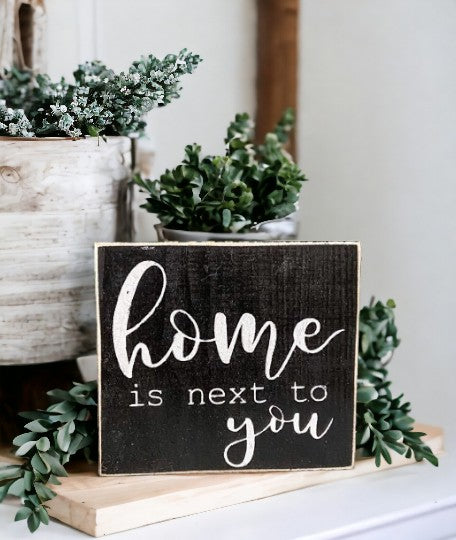 Home is Next to You" wooden block sign with black background and white text, perfect for shelf or tabletop display.