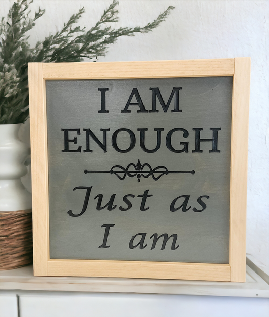 A 9.5" x 9.5" carved wood sign with a dark charcoal gray background and meticulously carved jet black text that reads, 'I am enough, just as I am.' This inspirational wall art is a powerful daily affirmation and a stunning addition to your space.