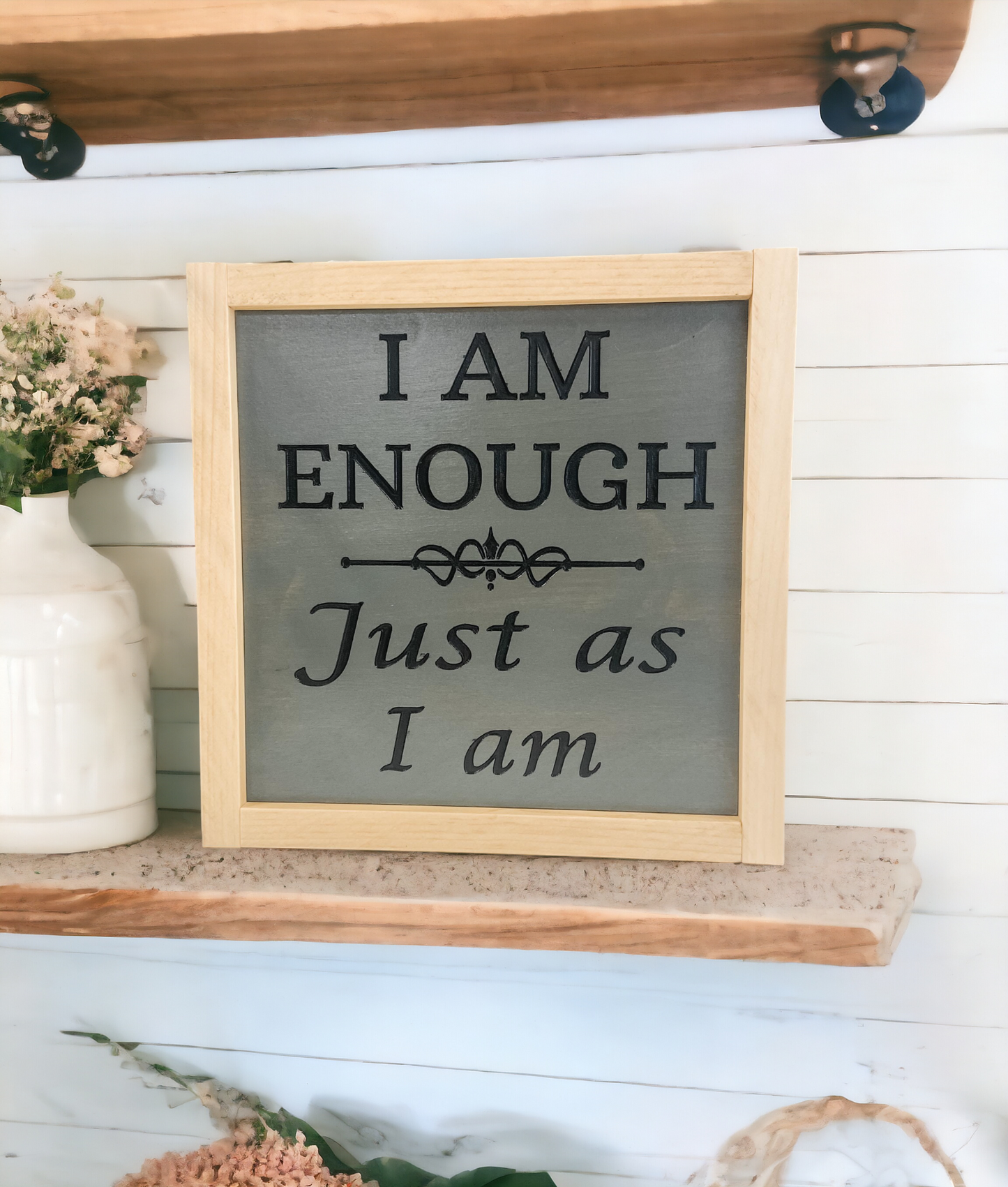 A 9.5" x 9.5" carved wood sign with a dark charcoal gray background and meticulously carved jet black text that reads, 'I am enough, just as I am.' This inspirational wall art is a powerful daily affirmation and a stunning addition to your space.