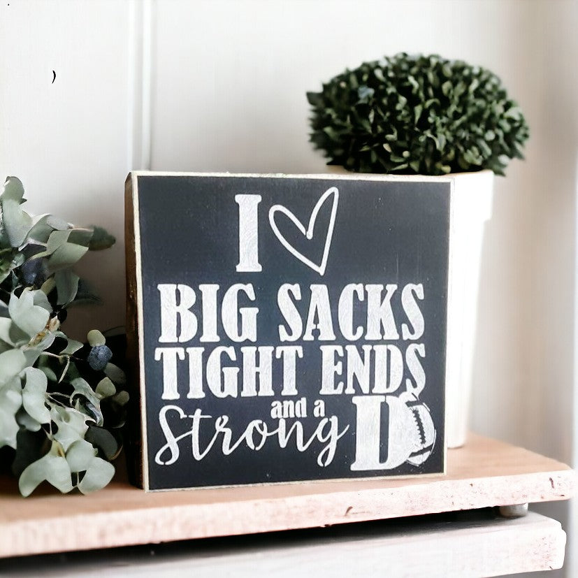 Mini wood football sign with humorous phrase "I love big sacks, tight ends, and a strong D", measuring approximately 5.5" x 5.5