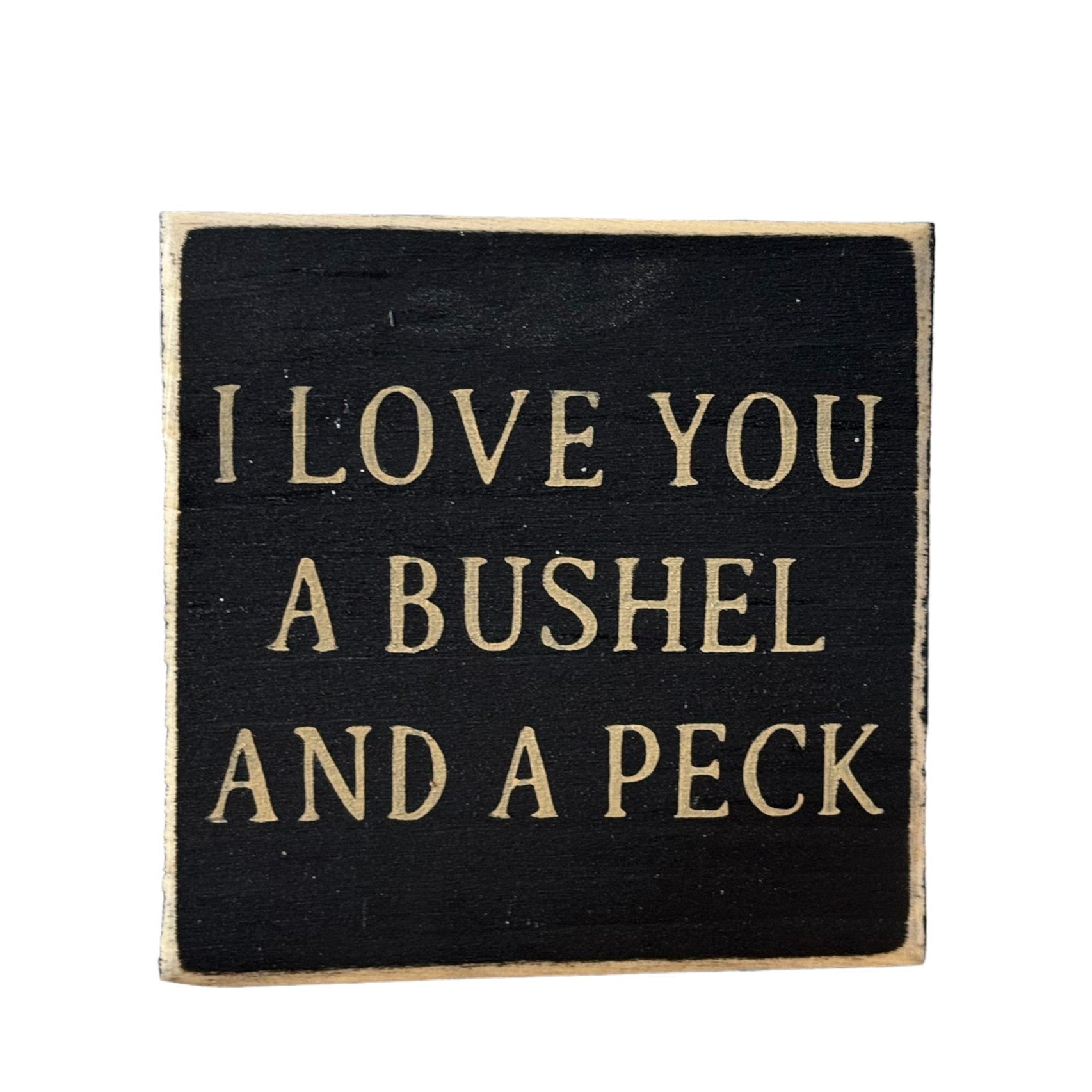 Hand-painted wooden block sign with black background and khaki text that reads 'I Love You a Bushel and Peck'