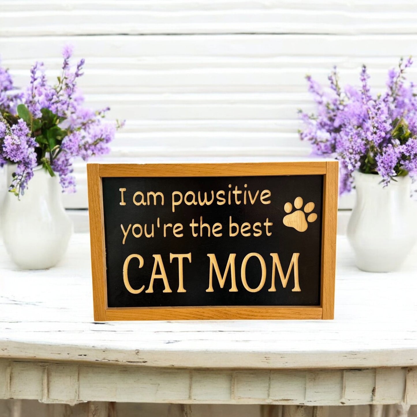 Framed carved wooden sign reading 'I'm Pawsitive You're the Best Cat Mom,' handpainted black with natural wood lettering and a stained frame. Perfect cat mom gift and cat decorations, ready to hang with attached hardware.