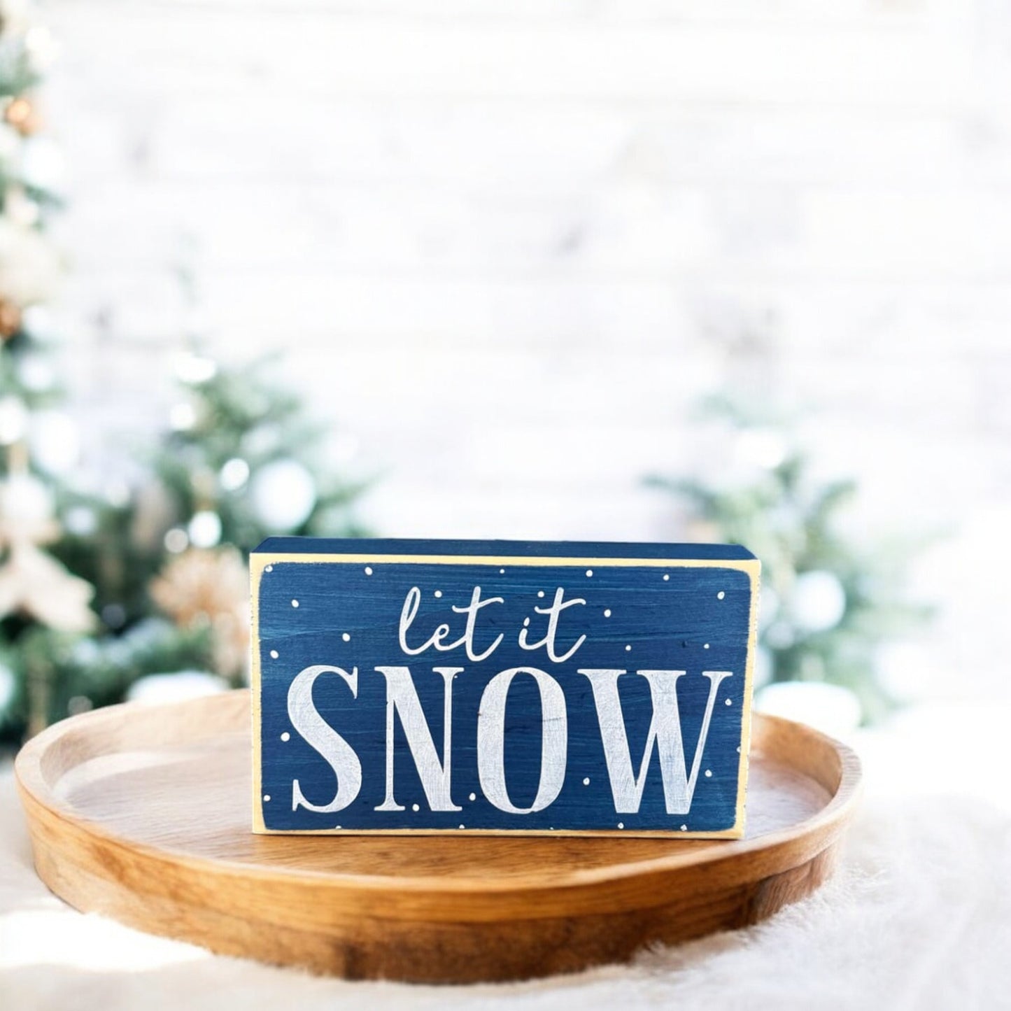 Handpainted wood block sign reading “Let It Snow” on a navy blue background, adorned with white text and snowflakes, perfect for winter decorations for the home.