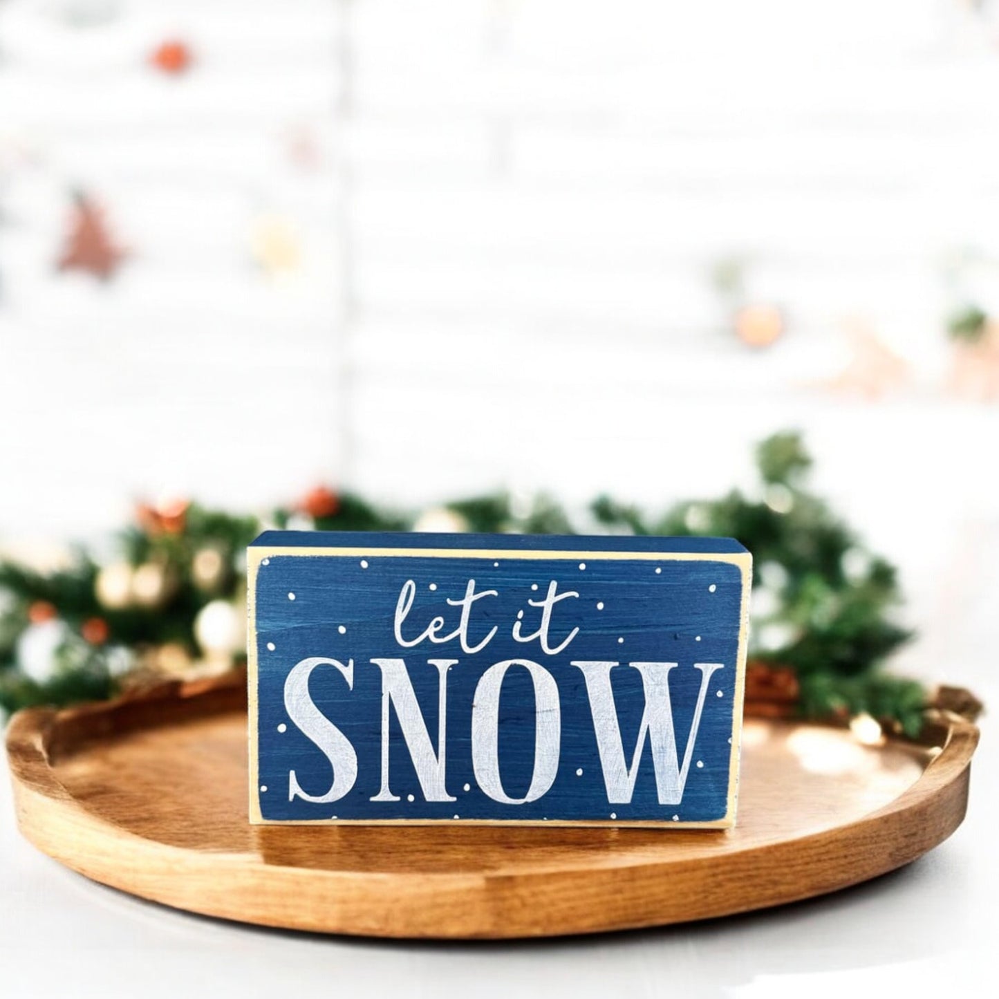 Winter-themed wood block sign with navy blue background and white lettering saying “Let It Snow,” designed for cozy home winter decorations.