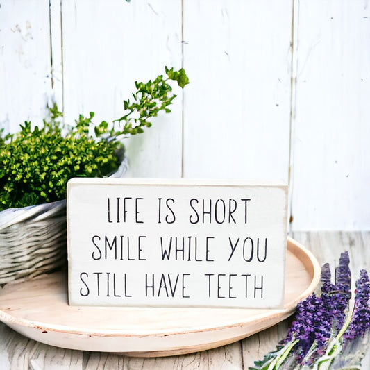 Life Is Short Smile While You Still Have Teeth" funny wood sign with black text on white background.