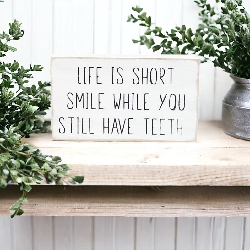 Life Is Short Smile While You Still Have Teeth" funny wood sign with black text on white background.