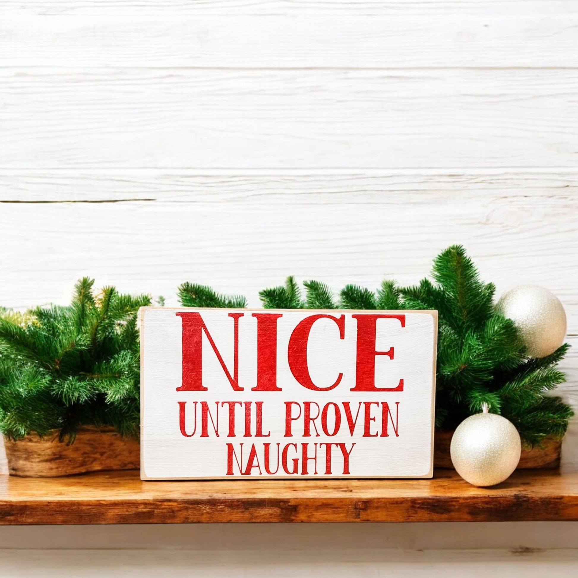 3.5" x 6" wood block sign reading "Nice until proven naughty," handpainted white with festive red holiday font.






