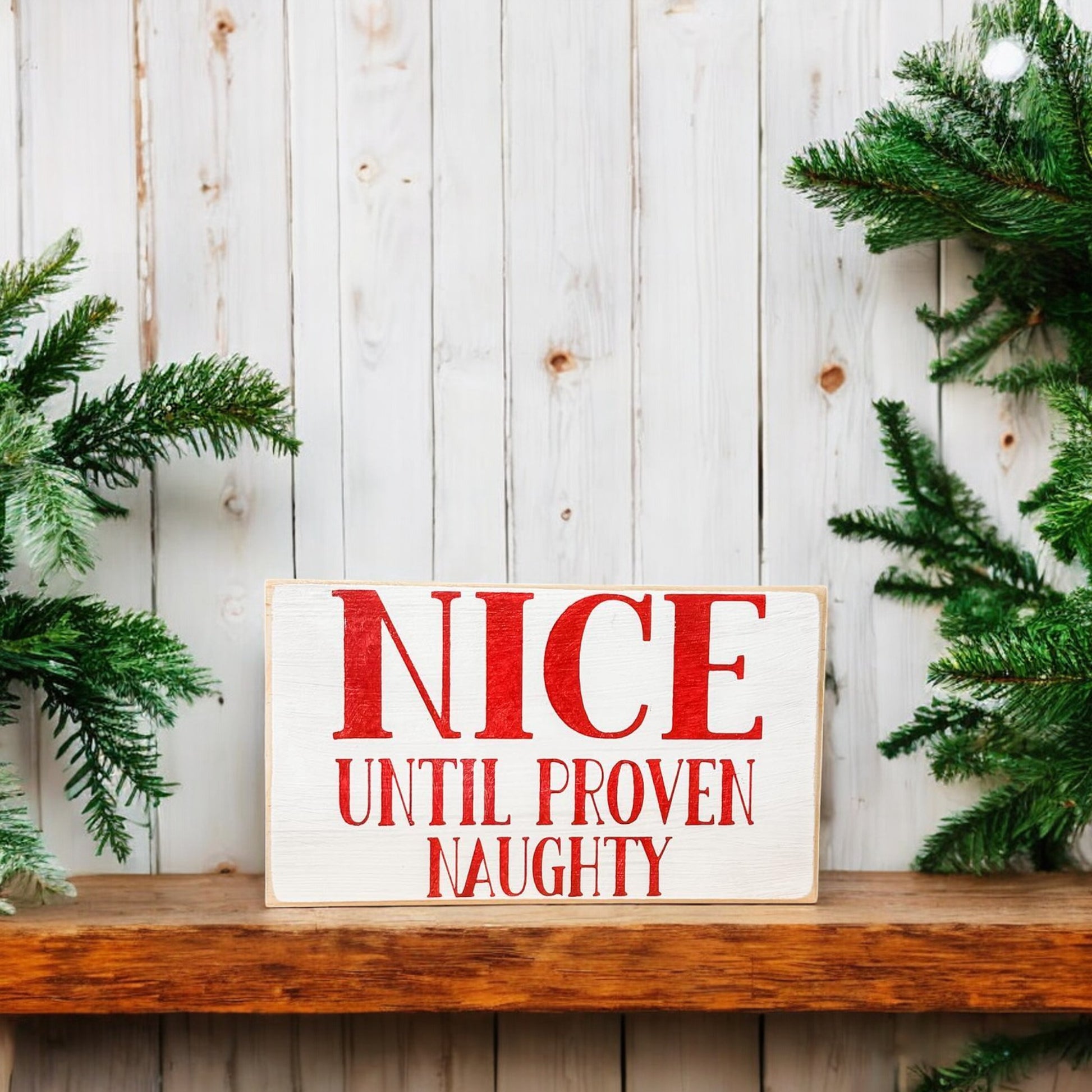 3.5" x 6" wood block sign reading "Nice until proven naughty," handpainted white with festive red holiday font.






