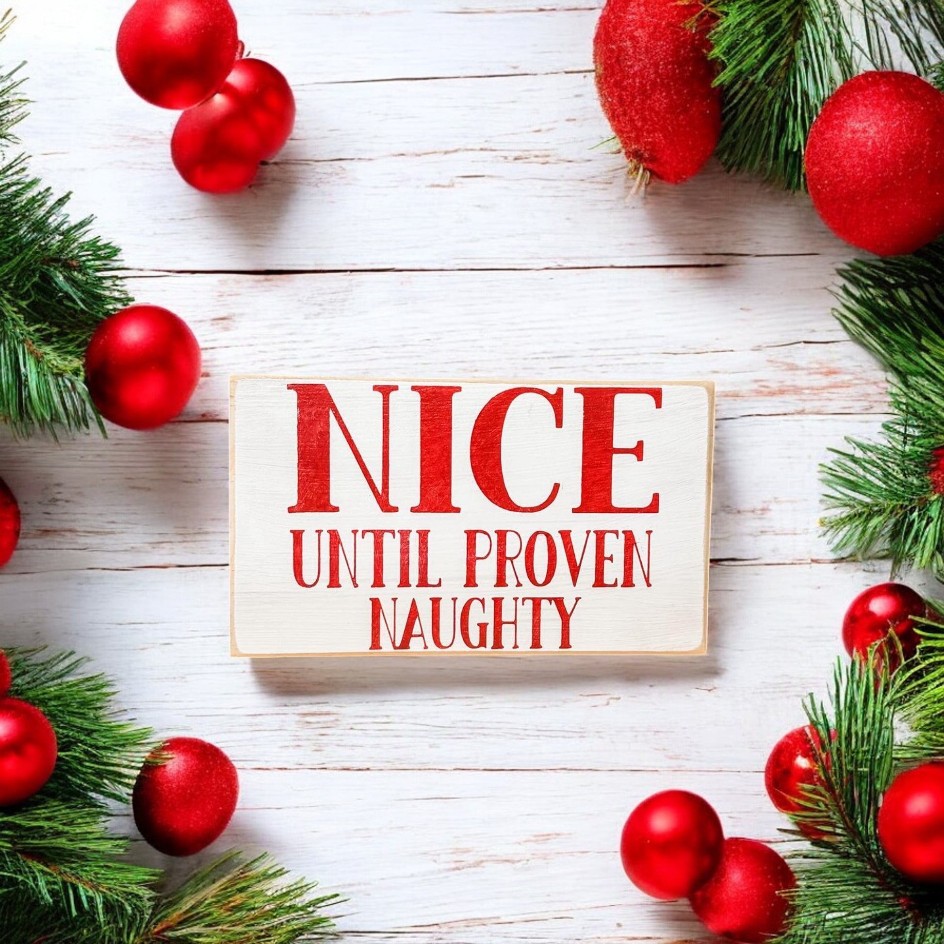 3.5" x 6" wood block sign reading "Nice until proven naughty," handpainted white with festive red holiday font.






