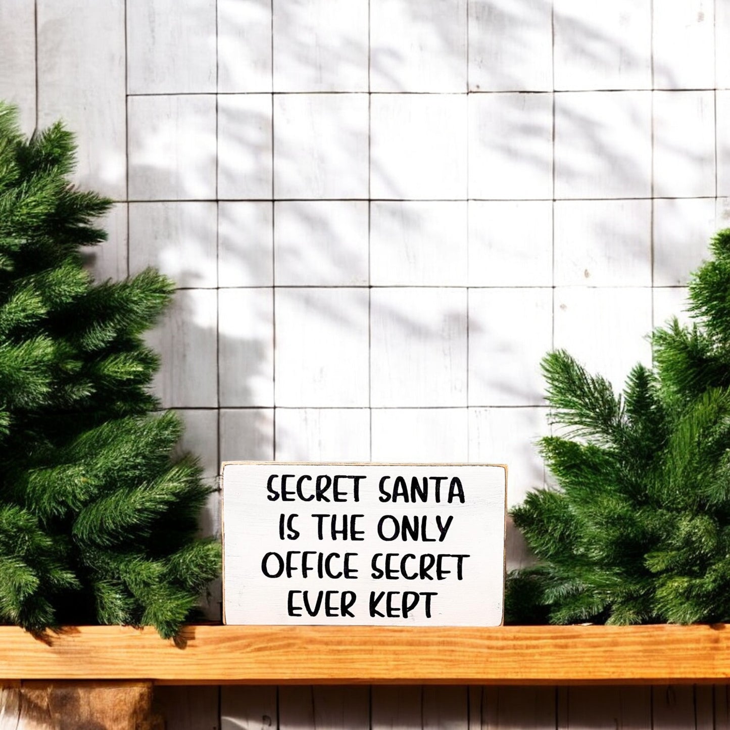 3.5" x 6" wood block sign reading "Secret Santa is the only office secret ever kept," handpainted with a white background and playful black text.