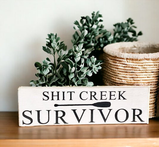 Shit Creek Survivor" funny wood sign hand-painted in white on a black background