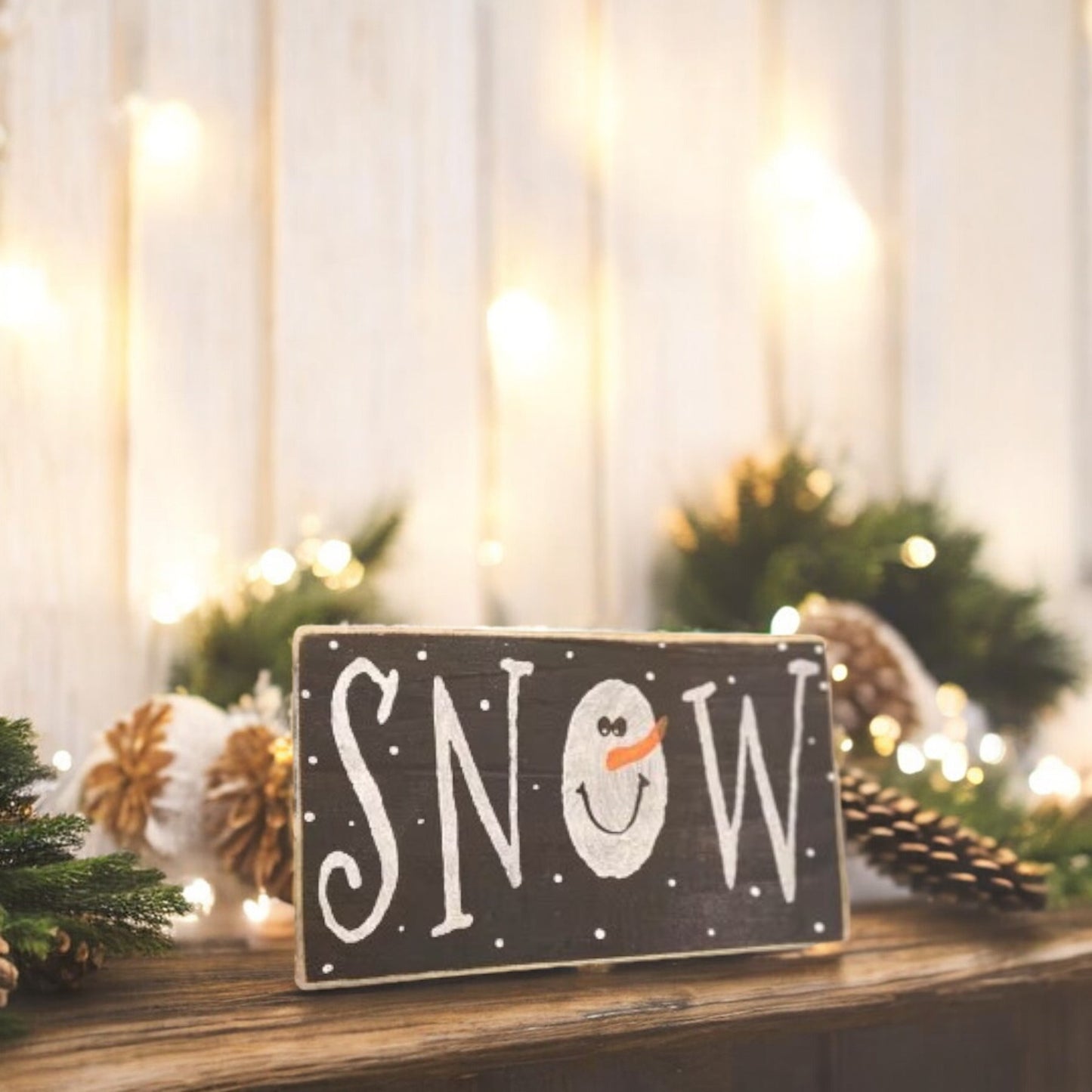 Primitive "Snow" wood block sign with a handpainted snowman as the "O" in snow, black background with white text.

