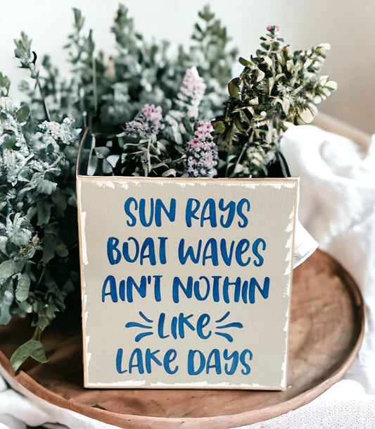 Image of a grey wooden sign with navy blue text that reads 'Sun rays, boat waves, ain't nothin' like lake days.' Perfect lake life decor