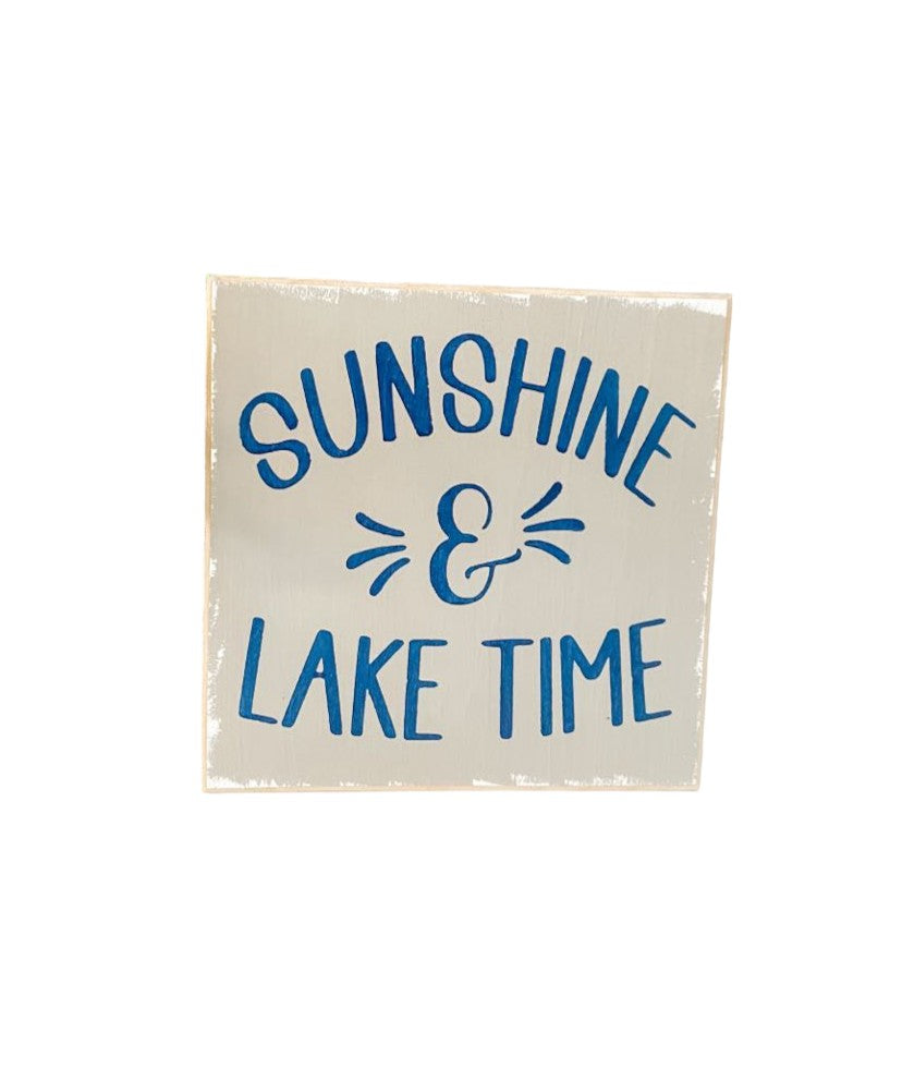 Image of a handcrafted grey wooden sign with navy blue text that reads 'Sunshine and Lake Time,' ideal for summer home decor.