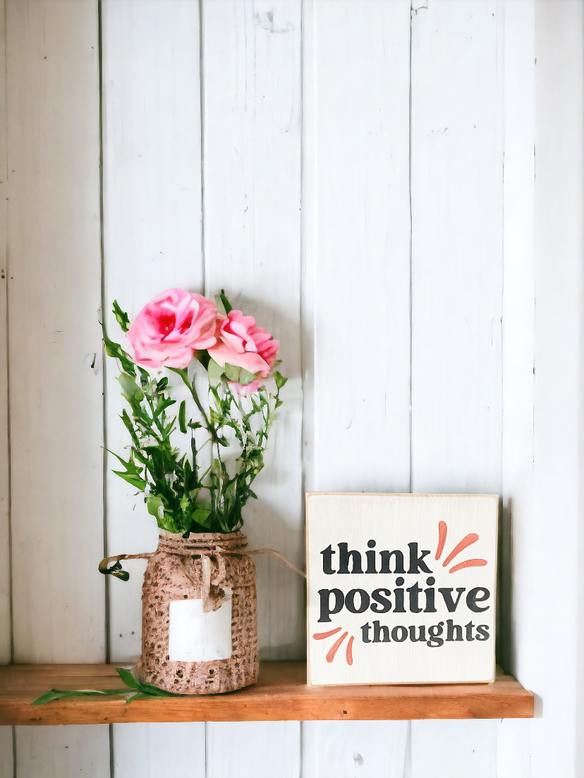 A 4.5" x 4.5" wood sign with inspiring modern black and pink text that reads 'Think Positive Thoughts' on a white background. This versatile wood sign is ideal for inspiring office decor or uplifting your home space, offering a daily dose of optimism and motivation
