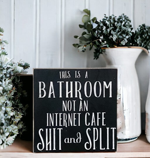 Funny bathroom sign with white text on black background, reading 'This is a bathroom not an internet cafe, shit and split