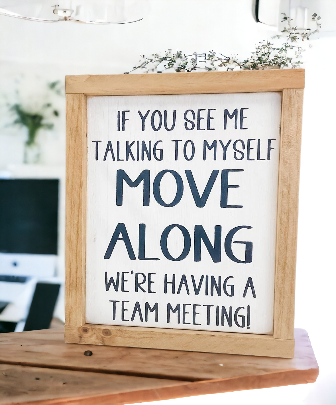 A framed wooden sign measuring 8" x 9.25". The sign features the humorous text, 'If you see me talking to myself, move along, we're having a team meeting.' This funny wood sign makes a great coworker gift and adds a playful touch to any office space.