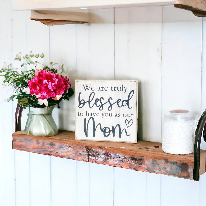 A 4.5" x 4.5" wood sign with a white background and elegant black text that reads, 'We are truly blessed to have you as our mom.' This unique mom gift is a heartwarming addition to your holiday decor, perfect for surprising your mom this Christmas.