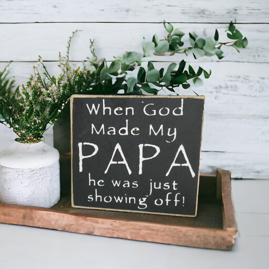 A 4.5" x 4.5" funny wood sign with a striking black background and bold white text that reads, 'When God Made My Papa He Was Just Showing Off.' This papa gift is a charming and humorous addition to your Papa's decor, suitable for any occasion or just because.